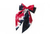 Handcrafted Afrocentric tie-dye satin bow in red, black, and white on white background