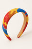 Afrocentric headband with vibrant yellow, red, and blue woven pattern on neutral background