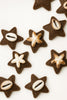 Handcrafted star-shaped brown cookies topped with cowrie shells and starfish on white background