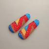 Afrocentric hair clips with vibrant red, blue, and yellow woven patterns on neutral background