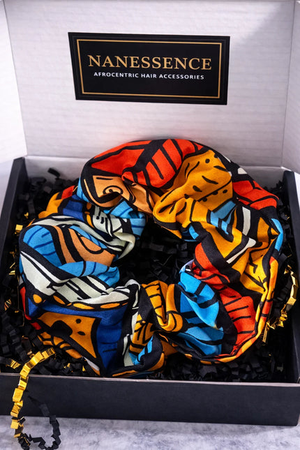Colorful Afrocentric patterned hair accessory scrunchie in a gift box with black and gold accents.