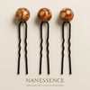 Three Afrocentric hair pins with brown marbled wooden beads and black wavy metal prongs.