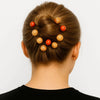 Woman with brown hair bun adorned with carved wooden and red beads, Afrocentric hair accessory