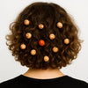Back view of curly hair adorned with carved wooden and red hair beads on white background