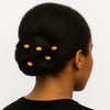 Woman with natural hair in a low bun adorned with Afrocentric red, yellow, and green hair pins