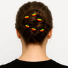 Woman with brown hair in a bun adorned with Afrocentric tricolor hairpins, rear view