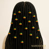 Back view of woman with long black locs adorned with green, yellow, and red Afrocentric beads