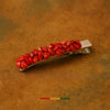 Afrocentric hair clip with red stone beads on metallic base, styled on brown background