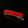 Handcrafted silver hair clip adorned with vibrant red beads on black background