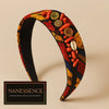 Afrocentric fabric headband with colorful tribal patterns, adorned with coral beads, buttons, and cowrie shell, ideal for statement hair accessories.