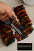 Hand holding colorful Afrocentric fabric hair clip with geometric patterns and rhinestone detail