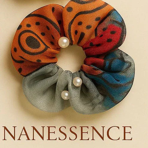 Afrocentric fabric scrunchie with orange, blue, and gray patterns and pearl accents