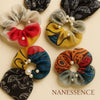 Afrocentric patterned chiffon hair scrunchies with pearl accents, assorted colors, flat lay.