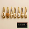 Set of gold hair clips with assorted natural seashells, Afrocentric fashion accessory display.